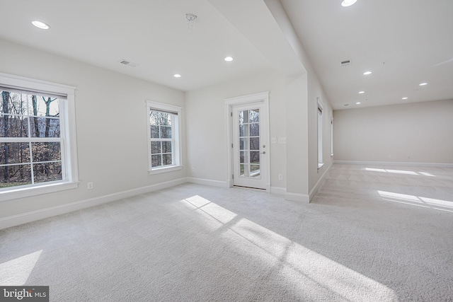 spare room featuring carpet floors, recessed lighting, plenty of natural light, and baseboards