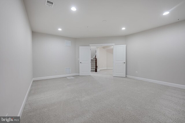 below grade area with recessed lighting, baseboards, light colored carpet, and stairs
