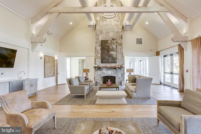 living area with high vaulted ceiling, a stone fireplace, light wood-style flooring, beamed ceiling, and french doors