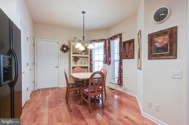dining room with a chandelier, light wood-style floors, and baseboards