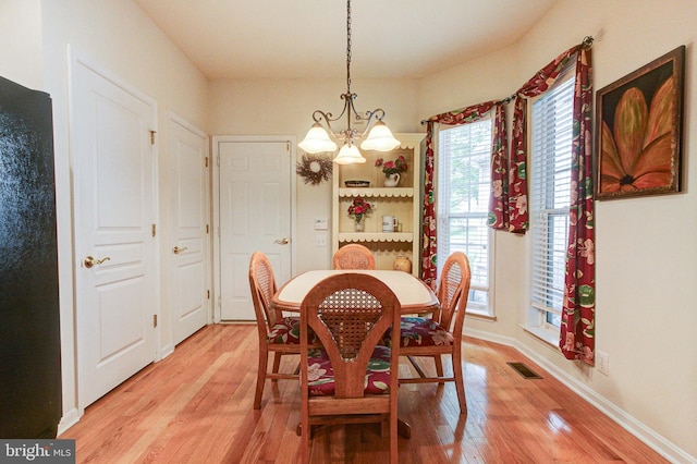 dining space with light wood-style floors, a chandelier, and baseboards