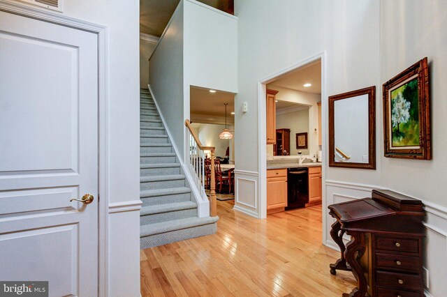 foyer featuring stairway, light wood-type flooring, wainscoting, and a decorative wall