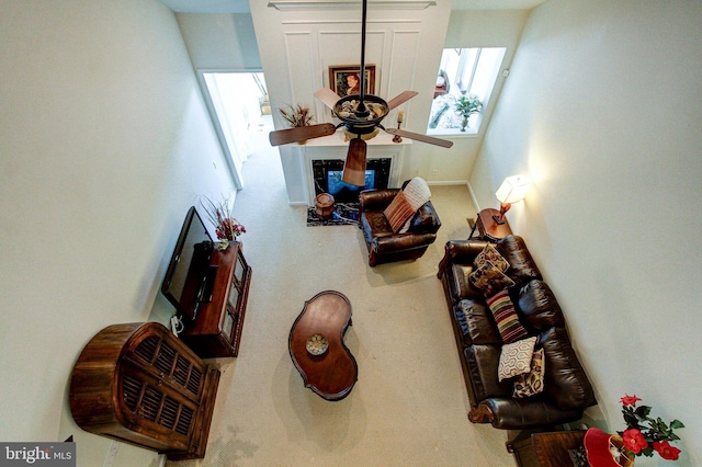 carpeted living area featuring a fireplace and a ceiling fan