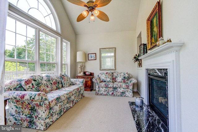 carpeted living room with ceiling fan, high vaulted ceiling, and a premium fireplace
