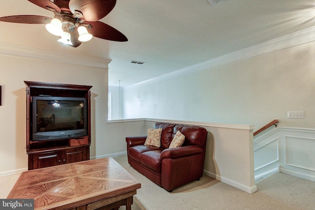 carpeted living area with a ceiling fan and ornamental molding