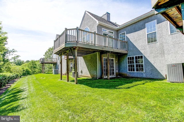 back of house with stucco siding, a deck, central AC unit, and a yard
