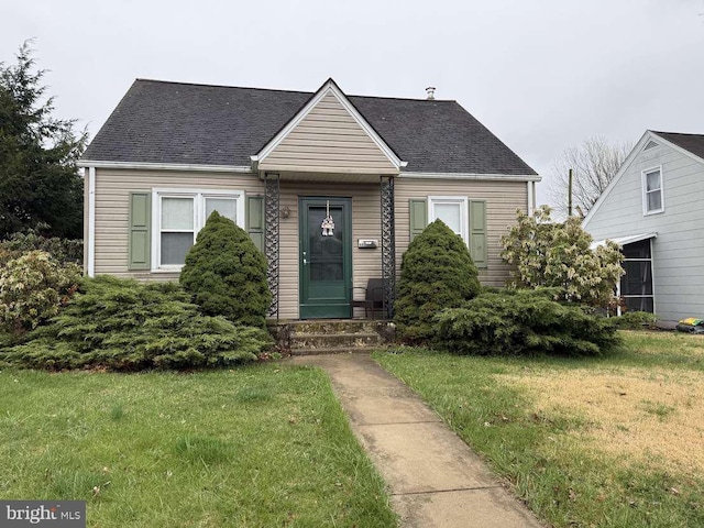 view of front facade featuring a front yard and roof with shingles