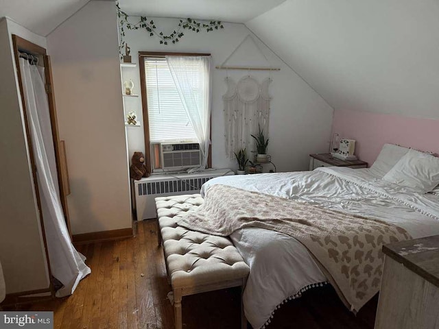 bedroom with radiator heating unit, cooling unit, lofted ceiling, hardwood / wood-style flooring, and baseboards