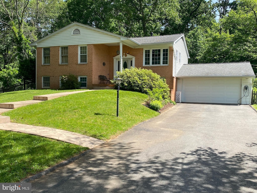 6205 Oak Hill Dr, Sykesville, MD 21784 - split foyer home featuring brick siding, a front yard, driveway, a garage, and view of scattered trees