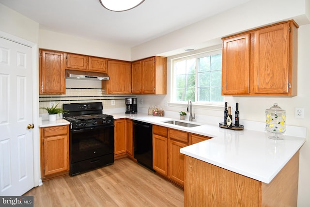 43193 Ribboncrest Ter, Ashburn, VA 20147 - kitchen with black appliances, under cabinet range hood, a peninsula, light wood-style floors, and light countertops