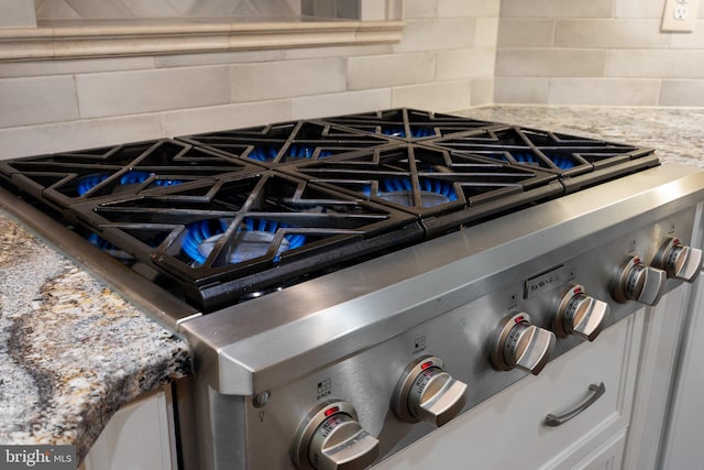 410 Metropolitan Blvd, Pasadena, MD 21122 - detailed view of backsplash, light stone counters, white cabinetry, and cooktop