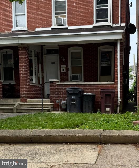 view of front of house with brick siding, cooling unit, and a porch