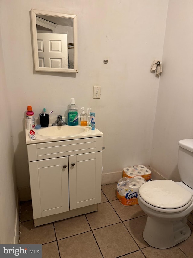 bathroom with toilet, vanity, and tile patterned flooring