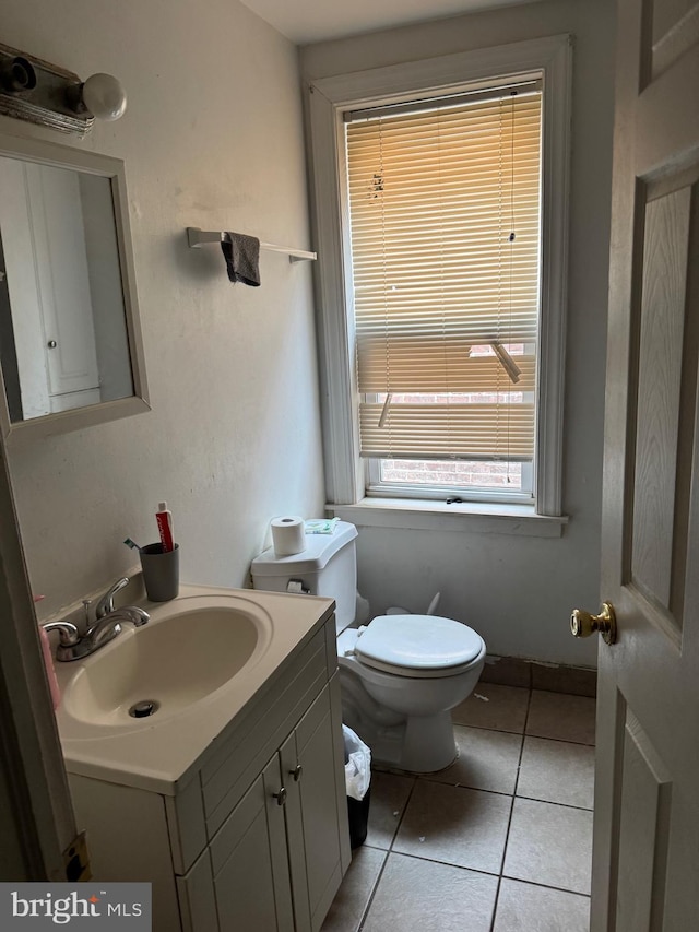 half bath featuring tile patterned floors, toilet, and vanity