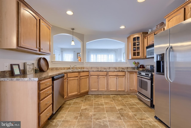 kitchen with stainless steel appliances, glass insert cabinets, a sink, hanging light fixtures, and recessed lighting
