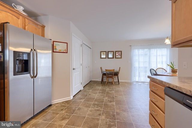 kitchen with stainless steel refrigerator with ice dispenser, dishwashing machine, light countertops, and baseboards
