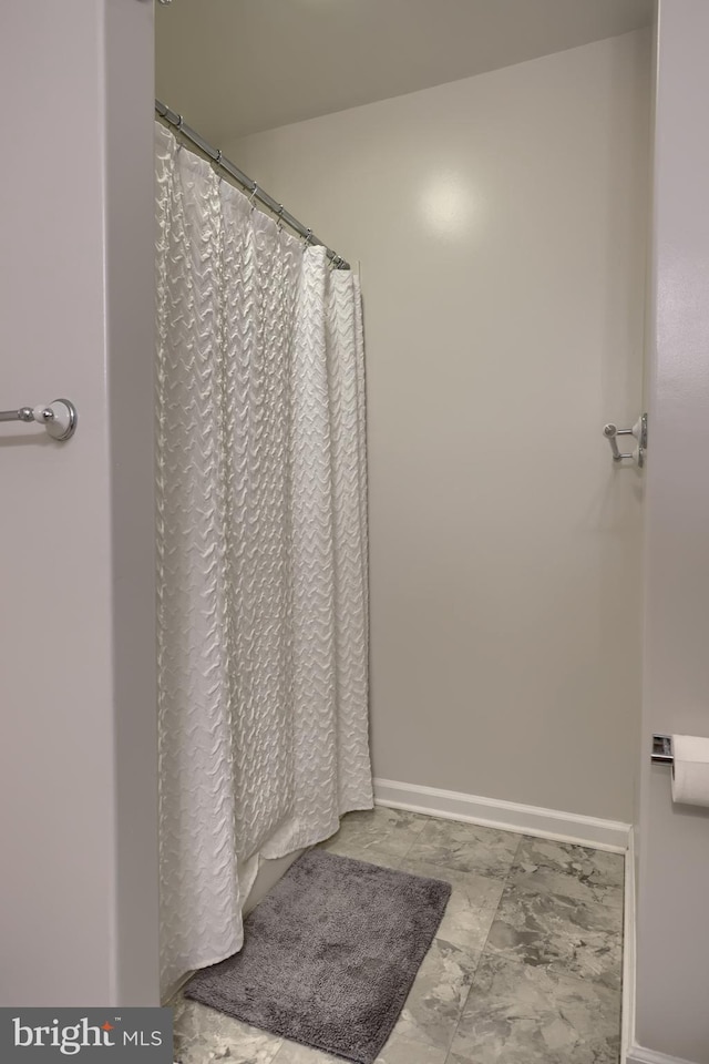 full bathroom featuring baseboards, marble look tiles, and curtained shower