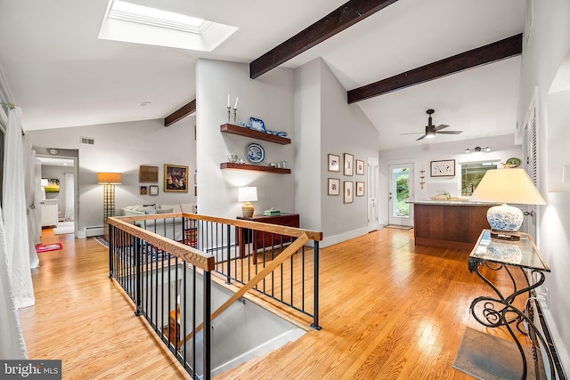 hallway featuring an upstairs landing, light wood-style floors, a baseboard radiator, and a skylight