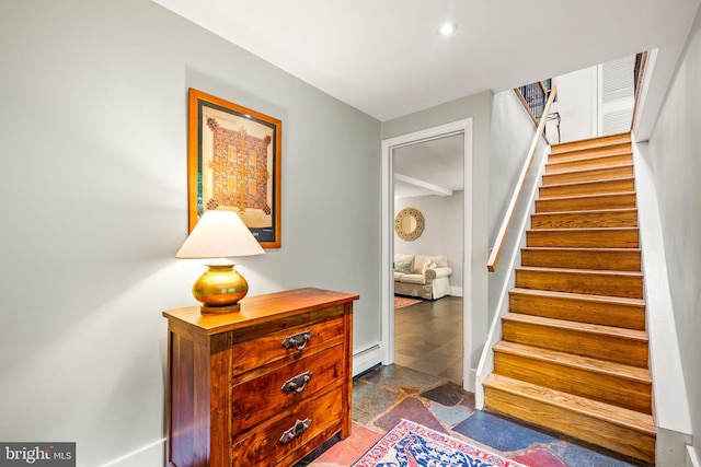 stairs featuring stone finish floors, a baseboard radiator, and baseboards