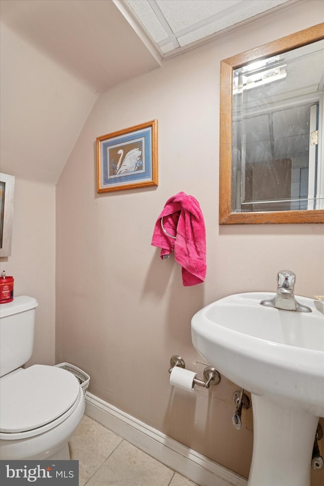 bathroom with toilet, tile patterned flooring, vaulted ceiling, and baseboards