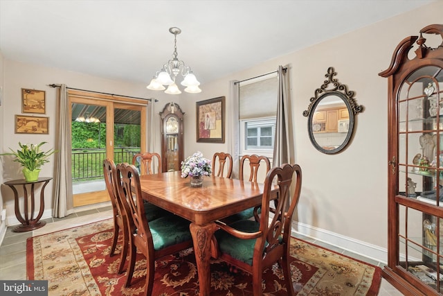 dining area featuring a chandelier, light tile patterned flooring, and baseboards