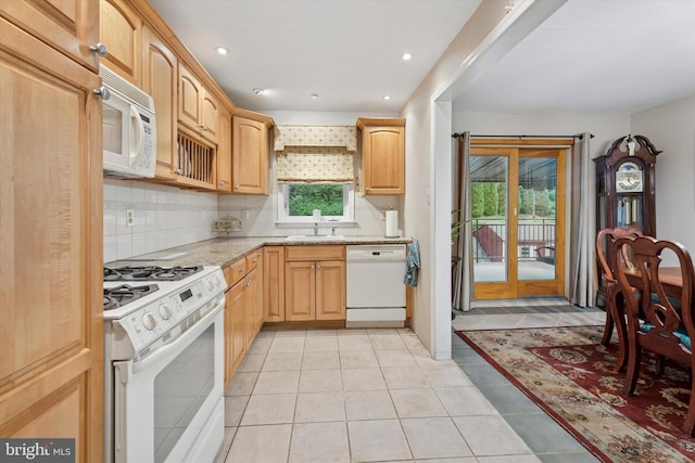 kitchen with white appliances, a sink, decorative backsplash, light stone countertops, and recessed lighting
