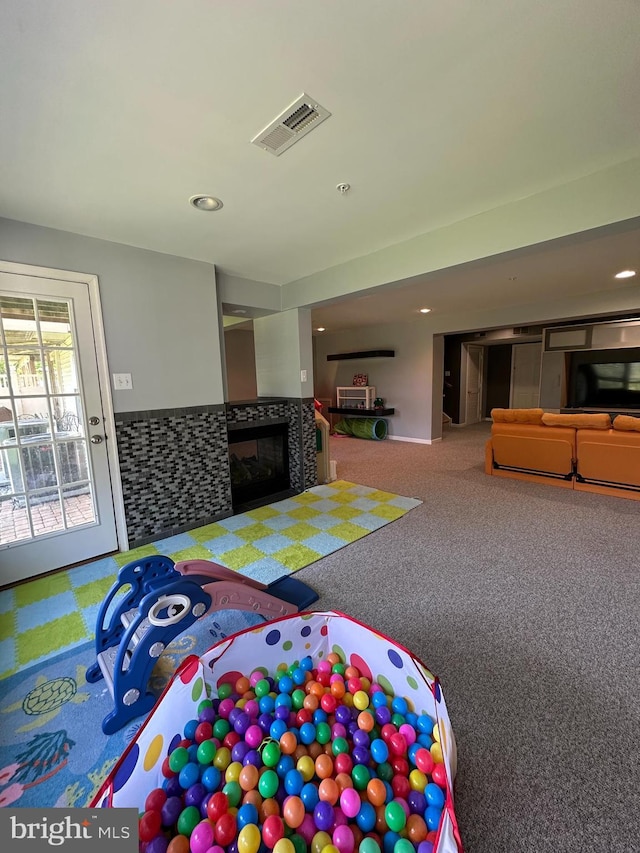 recreation room featuring a multi sided fireplace, carpet, and recessed lighting