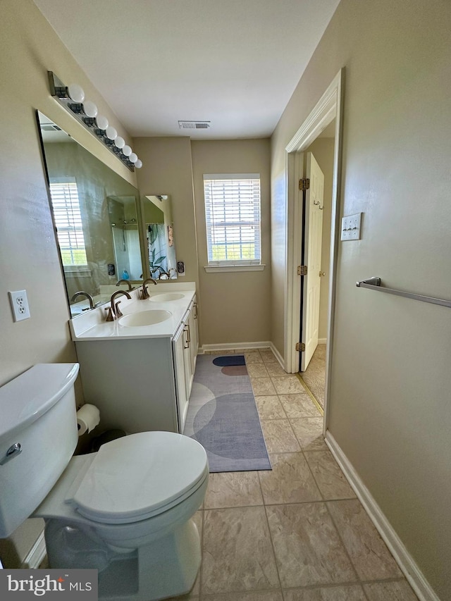 bathroom featuring toilet, double vanity, baseboards, and tile patterned floors