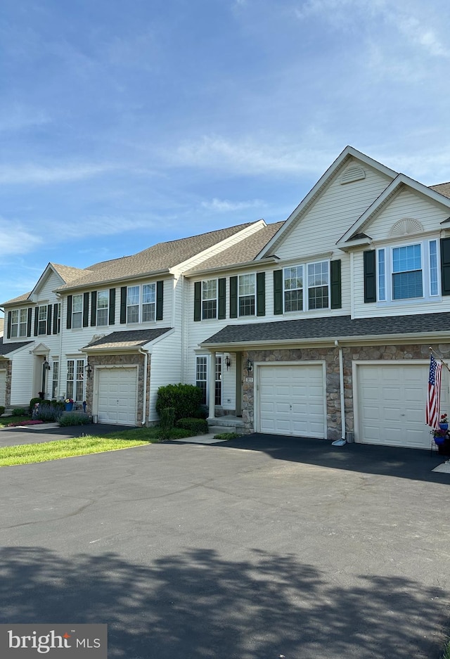 multi unit property with driveway, a garage, and a shingled roof