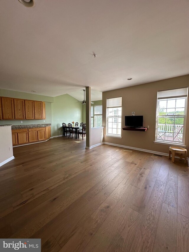 unfurnished living room featuring dark wood-style floors, healthy amount of natural light, and baseboards