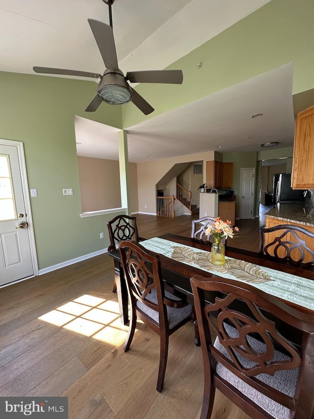 dining space featuring wood finished floors, a ceiling fan, and baseboards