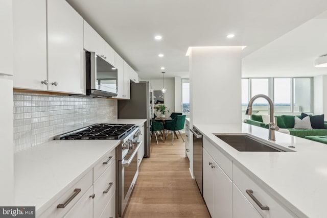 604 S Washington Sq Unit 2917, Philadelphia, PA 19106 - kitchen featuring appliances with stainless steel finishes, a sink, light wood-style flooring, decorative backsplash, and light countertops