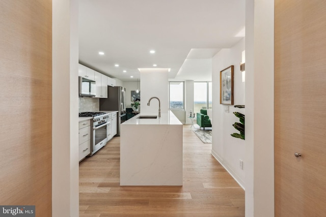 604 S Washington Sq Unit 2917, Philadelphia, PA 19106 - kitchen featuring high quality appliances, a sink, white cabinetry, light wood finished floors, and an island with sink