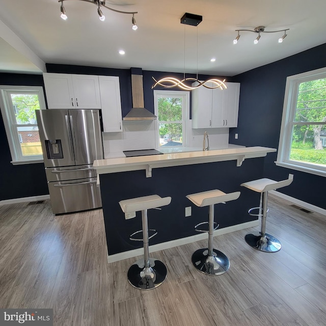 3608 Upshur St, Brentwood, MD 20722 - kitchen with wall chimney range hood, stainless steel fridge with ice dispenser, healthy amount of natural light, and light countertops