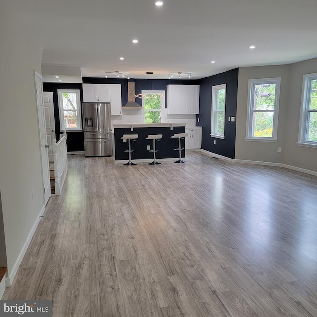 3608 Upshur St, Brentwood, MD 20722 - kitchen with stainless steel refrigerator with ice dispenser, wall chimney range hood, a center island, white cabinetry, and light wood finished floors