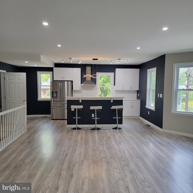 3608 Upshur St, Brentwood, MD 20722 - kitchen with stainless steel refrigerator with ice dispenser, wall chimney exhaust hood, white cabinetry, baseboards, and a breakfast bar