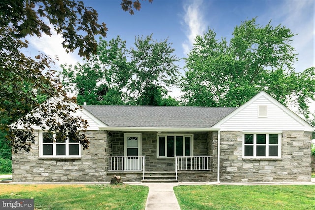 ranch-style house featuring stone siding, a porch, a front lawn, and roof with shingles