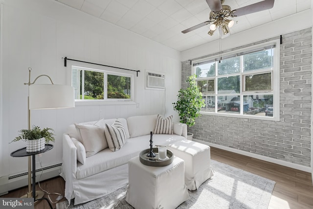 15415 Michigan Rd, Woodbridge, VA 22191 - living room featuring baseboard heating, wood finished floors, healthy amount of natural light, a wall mounted AC, and brick wall