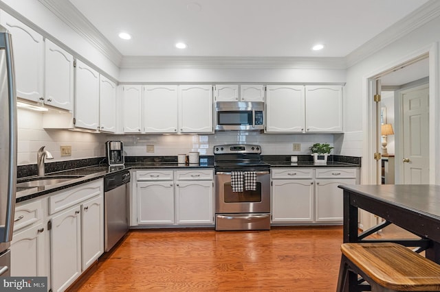 1153 Randolph Rd, Mclean, VA 22101 - kitchen with appliances with stainless steel finishes, ornamental molding, backsplash, white cabinetry, and light wood-style flooring