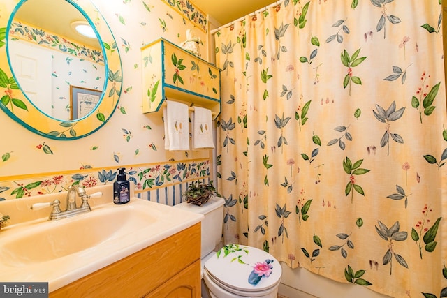 bathroom featuring wallpapered walls, toilet, vanity, and shower / bath combo