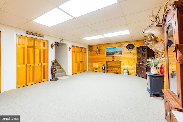 misc room with wooden walls, stairway, carpet flooring, and a paneled ceiling
