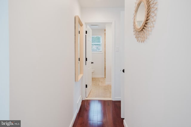 hall featuring dark wood-style flooring and baseboards