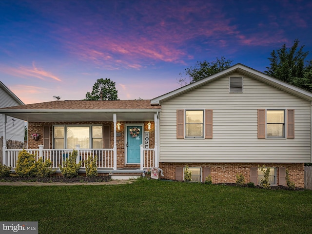 view of front facade featuring a porch, brick siding, and a lawn