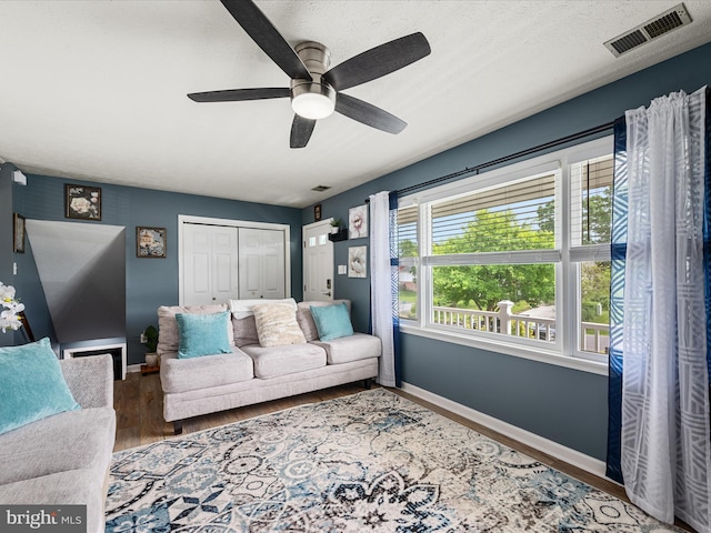 living area featuring baseboards, wood finished floors, and ceiling fan