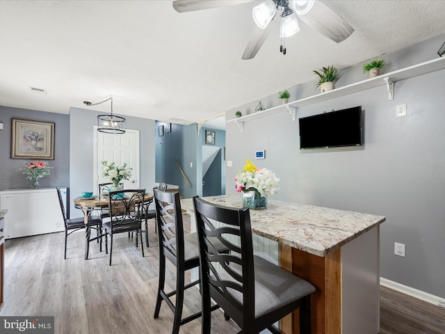 dining room with wood finished floors, ceiling fan, and baseboards