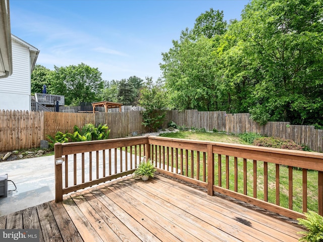 wooden deck with a fenced backyard and a patio