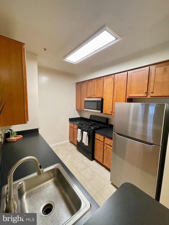 4862 Eisenhower Ave Unit 269, Alexandria, VA 22304 - kitchen with appliances with stainless steel finishes, a sink, dark countertops, light tile patterned floors, and brown cabinets