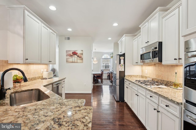 kitchen featuring stainless steel appliances, a sink, dark wood finished floors, recessed lighting, and light stone counters