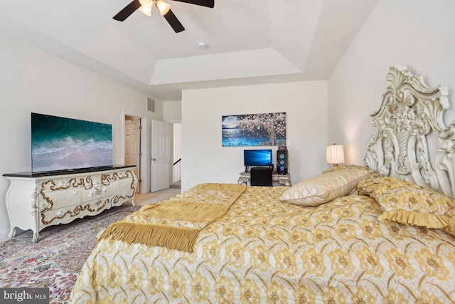 bedroom with a tray ceiling, a ceiling fan, and carpet flooring