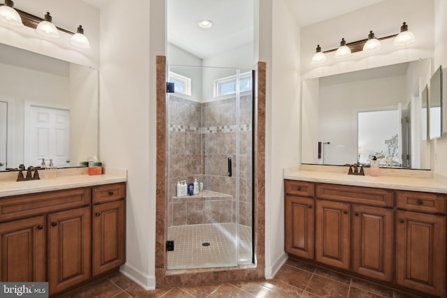 full bath featuring a stall shower, baseboards, two vanities, and tile patterned flooring
